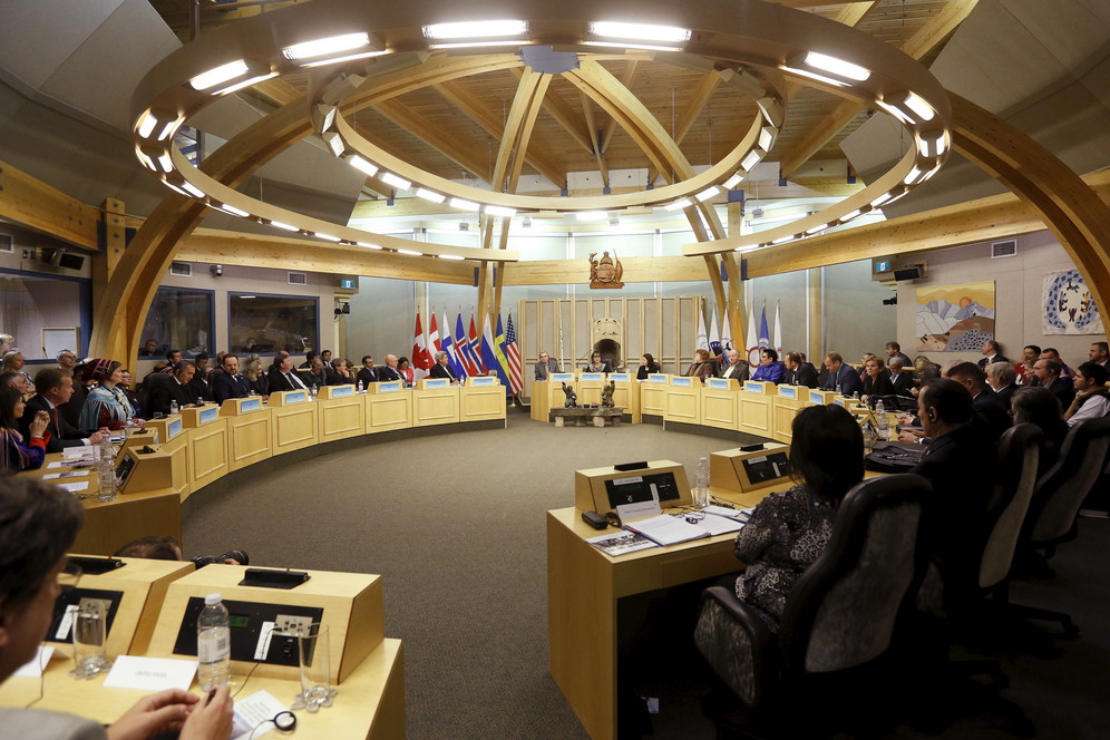 Dozens of Arctic Council delegates sit  around tables in spherical wooden building in Greenland